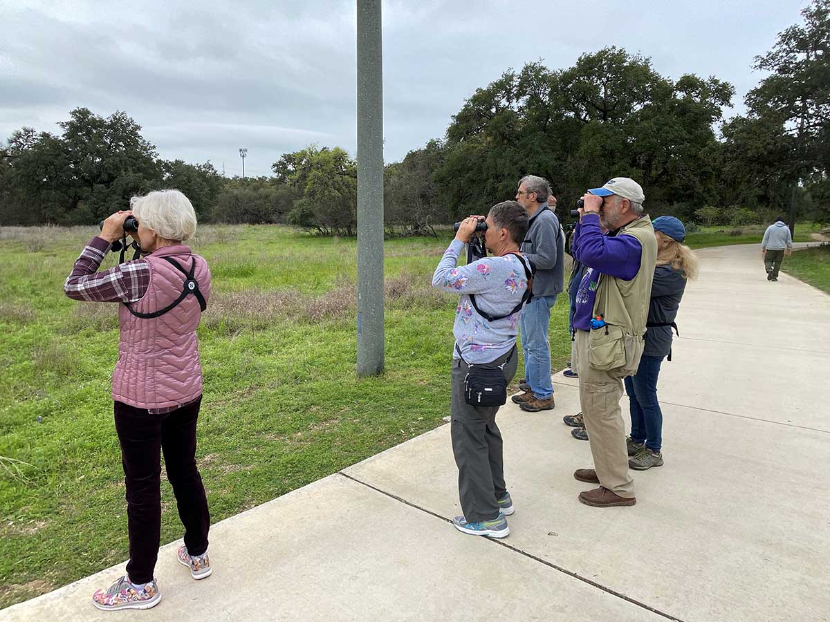 partial group shot of birding group looking at a bird