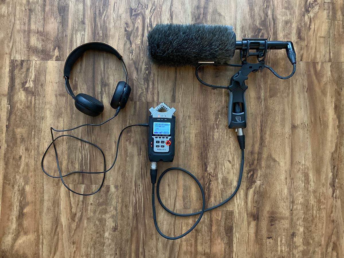 a photo of headphones, recording device, and shotgun microphone in handgrip